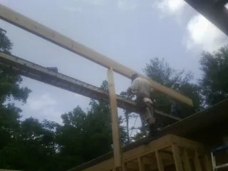 Carpenter setting a ridge beam over a new addition frame — Ice Dam Removal by Roofing Brothers in Bouckville