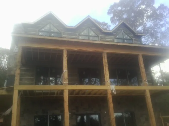 Dormers and porch framing on a large log home under construction — Roof Coating work by our crew in Bouckville