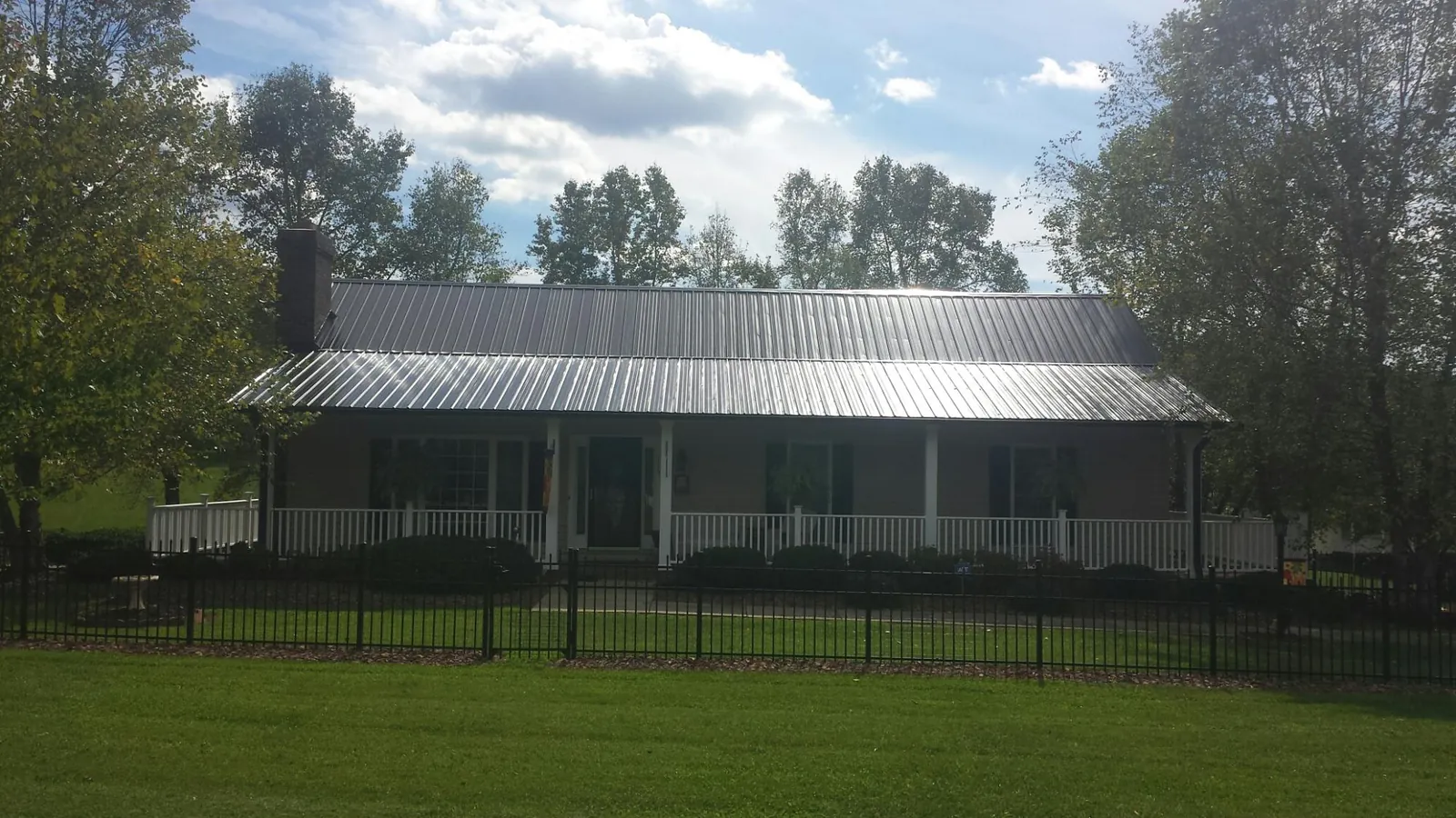Gray metal roof on a brick ranch with a full width front porch — Gutter Guard Installation work by our crew in Bouckville