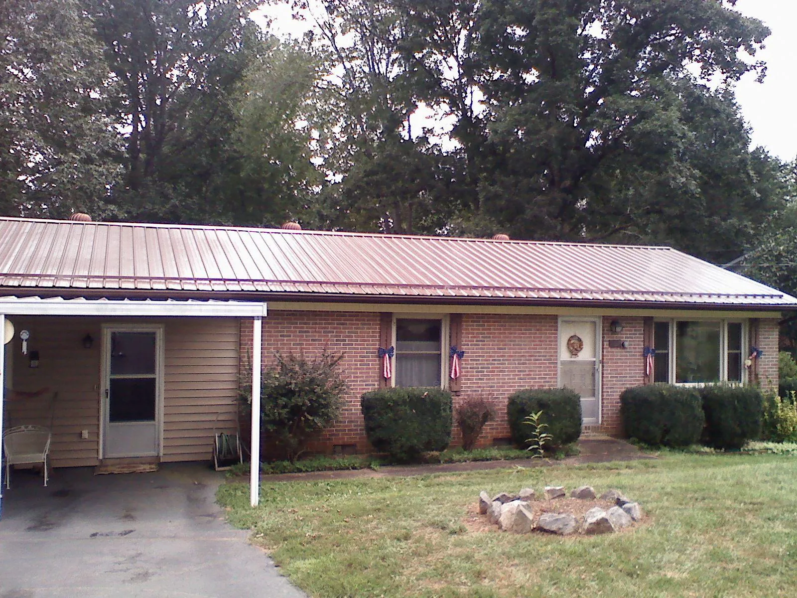 Bronze metal roof and carport on a brick ranch home — Roof Repair work by our crew in Bouckville