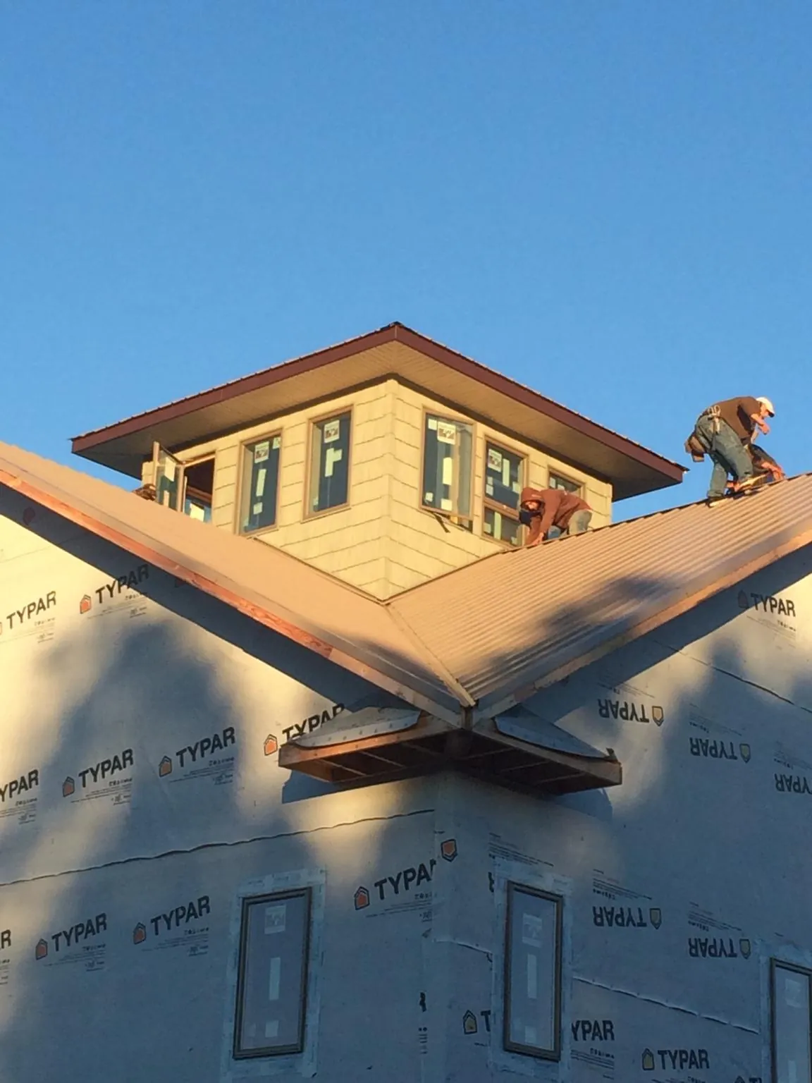 Roofers working around a rooftop cupola on a new metal roof at sunset — Roof Waterproofing in Bouckville by Roofing Brothers